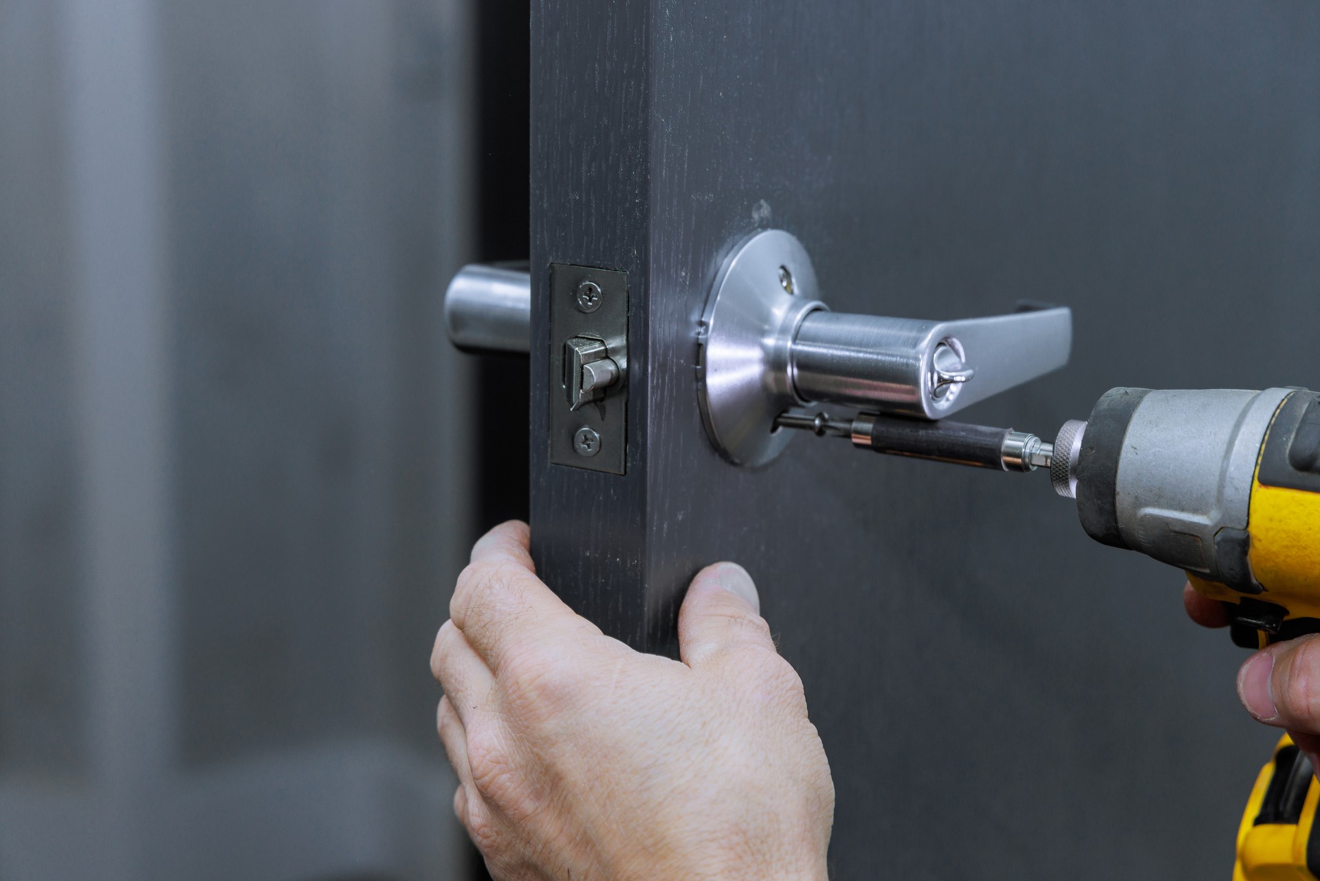 Installing lock handles on room doors with screwdriver by a carpenter